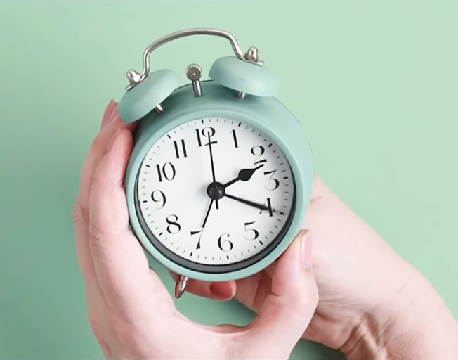 Hands adjusting the time on an old style alarm clock