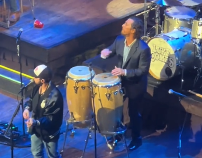 Matthew McConaughey playing bongos on stage at Luke Combs concert