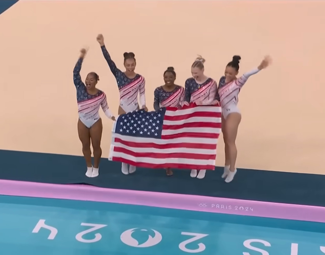 USA Gymnastics Team holding American flag at Paris Olympics 7-30-21