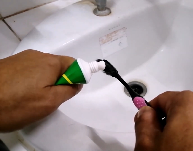 A person squeezing toothpaste out of a tube onto a toothbrush